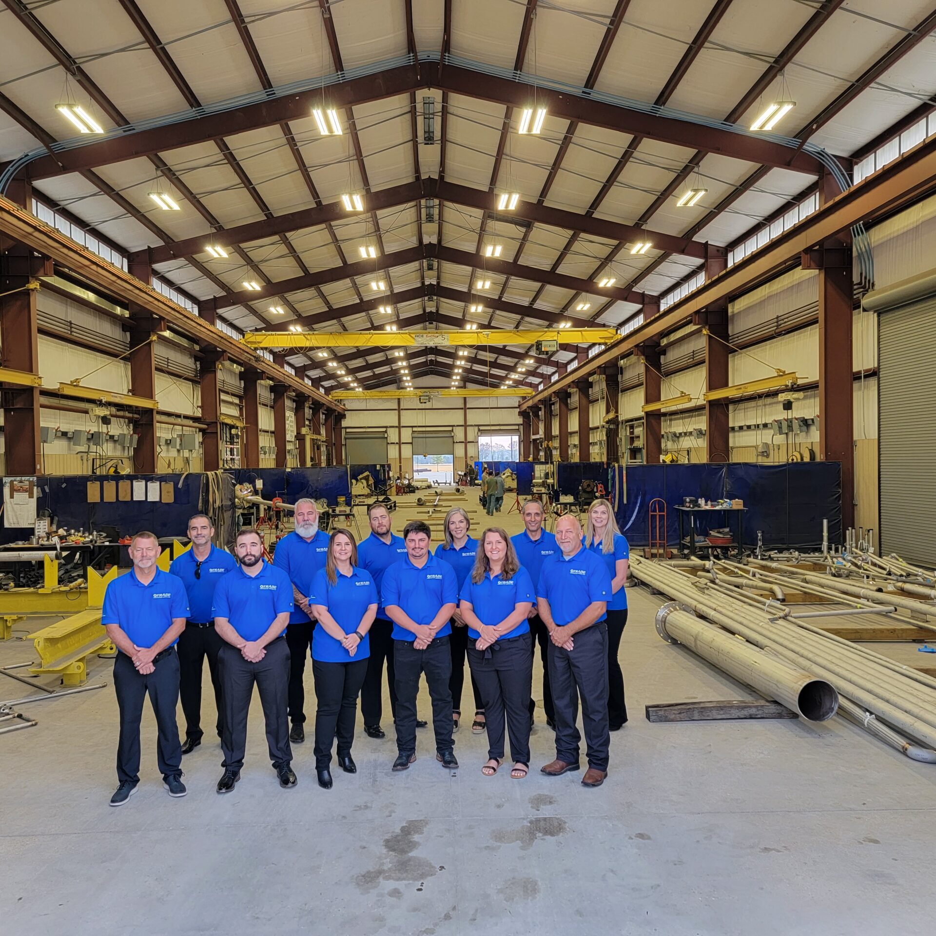 Twelve Trade team members standing for a group photo in a Trade warehouse.